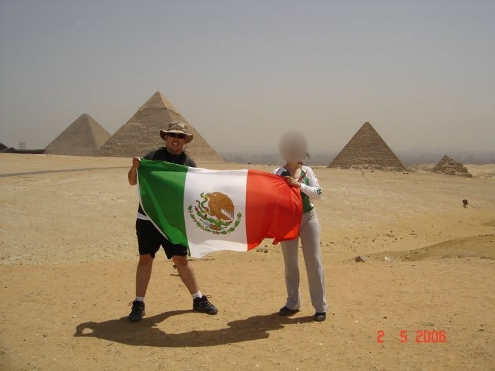 David y su esposa frente a las pirámides de Egipto con una bandera de México